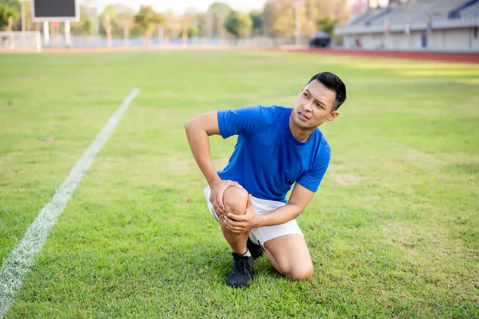 Athlete holding his knee after a sports injury on a field