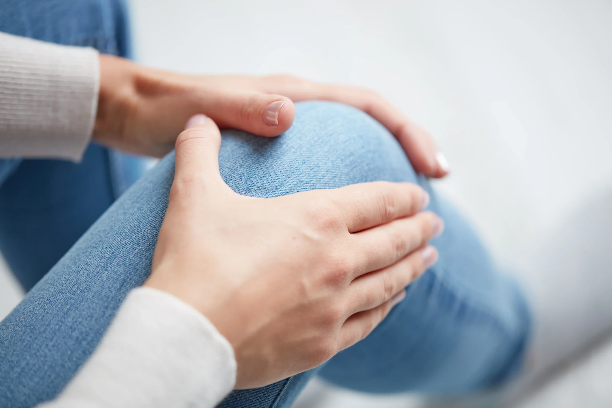 Patient holding painful knee for orthopaedic assessment