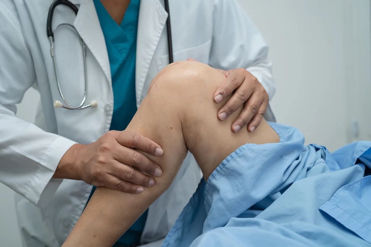 Orthopaedic doctor examining a patient's knee during osteoarthritis treatment assessment